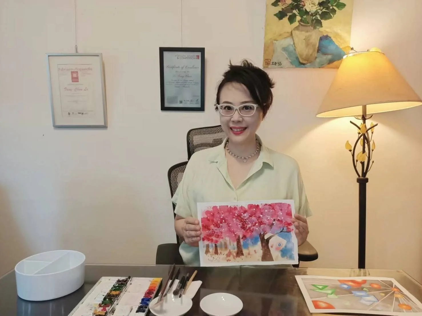 羅方君老師手持色彩鮮明的畫作，身旁可見畫具