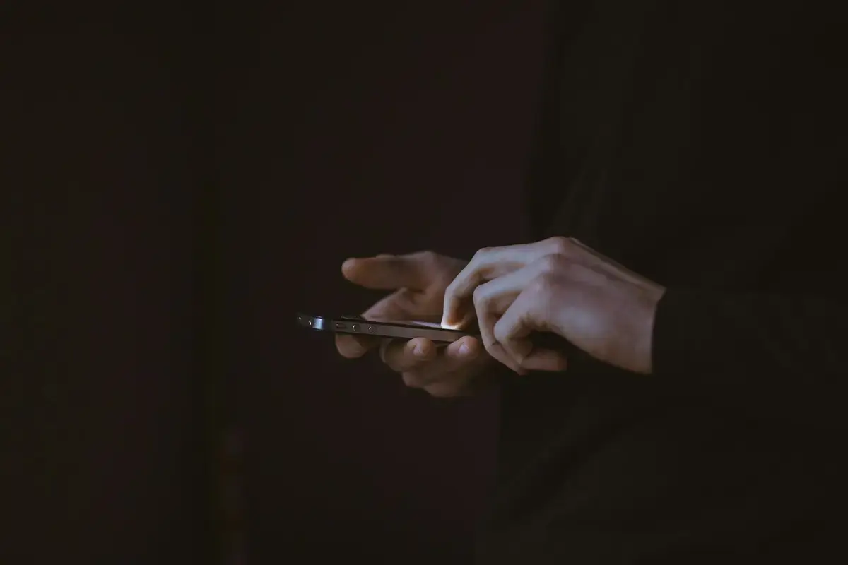 夜間有人滑手機瀏覽社群媒體（示意圖）