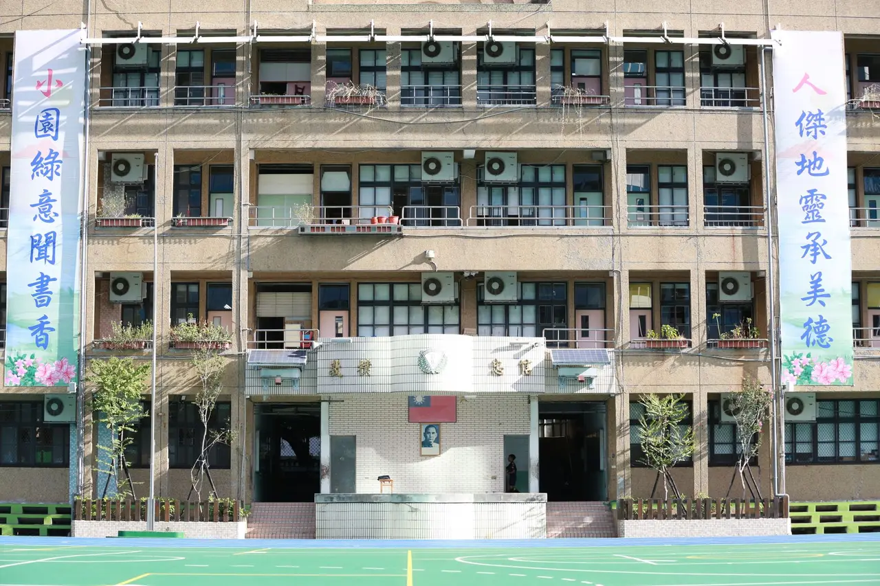 一群小學生揹著書包走向校園，象徵開學情境