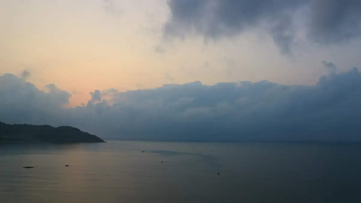 峴港海岸雨季降雨落在濕滑路面，近景呈現雨滴與水痕（示意圖）
