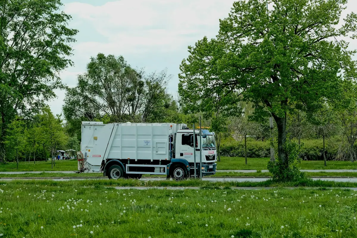 城市住宅街道上的垃圾車正在收運家戶垃圾，呈現垃圾車與街道生活的關係