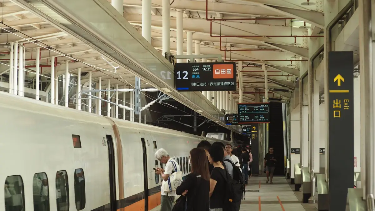 高鐵列車停靠月台，旁邊可見班次資訊看板與候車區