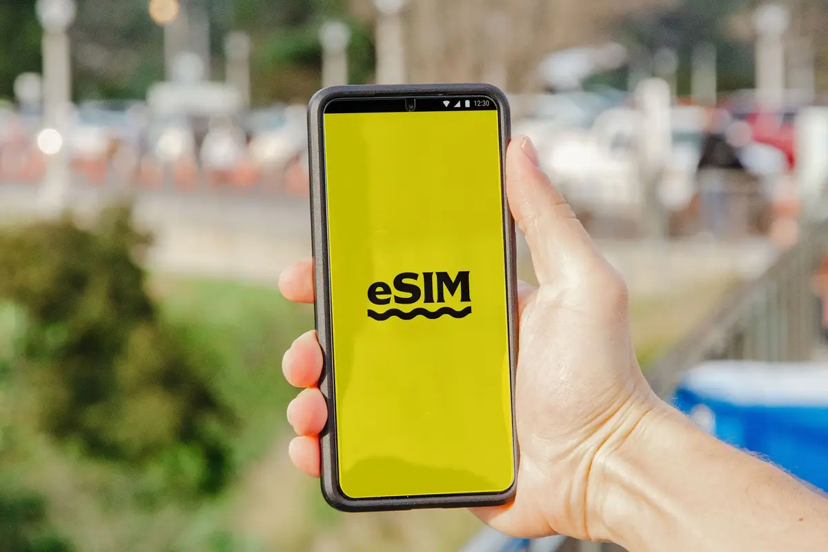 手機螢幕顯示 eSIM 字樣，呈現換機前準備數位門號的情境（示意圖）