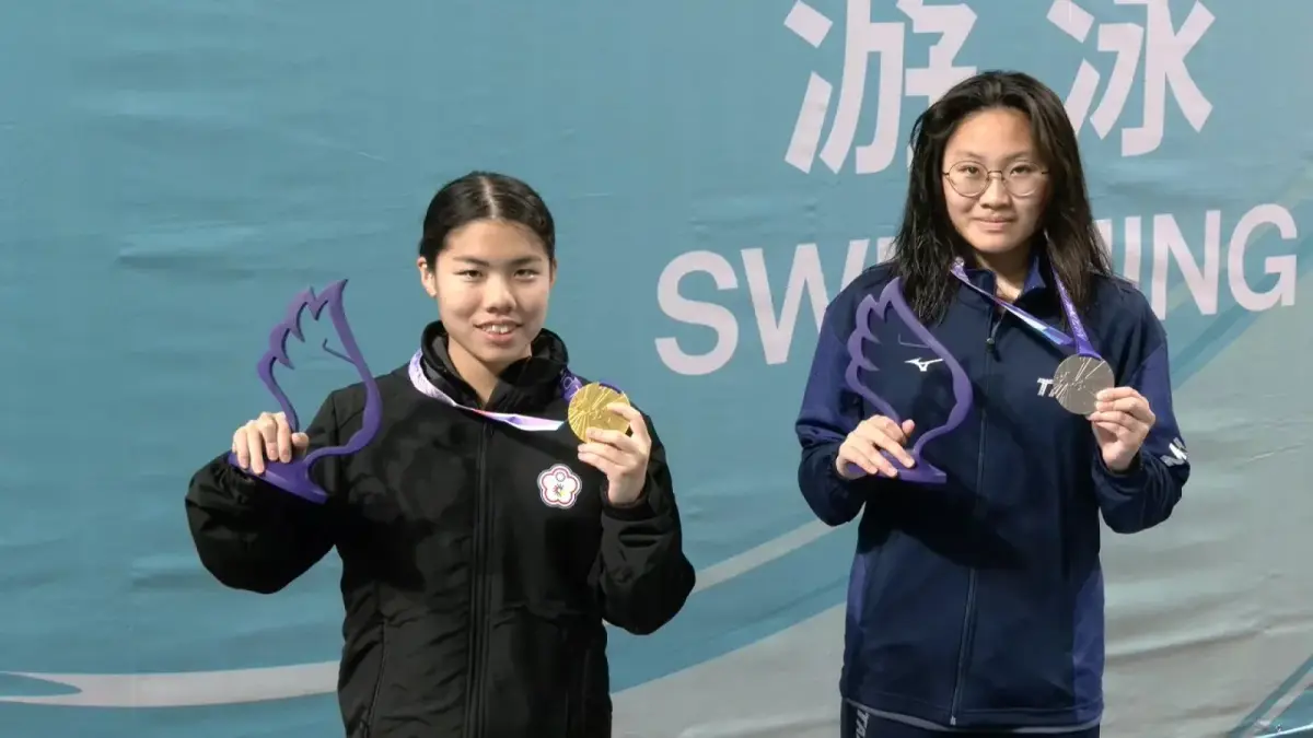 一名台灣年輕女選手在室內泳池第4水道進行自由式比賽，水花濺起且鄰近水道選手落後。