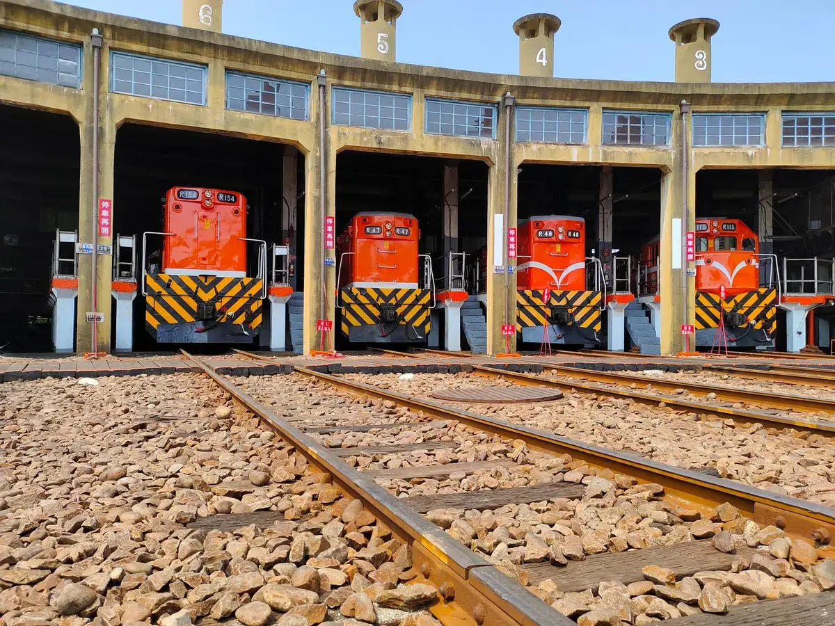 老糖廠機車庫前停放紅色柴油機車，軌道延伸至前景（示意圖）