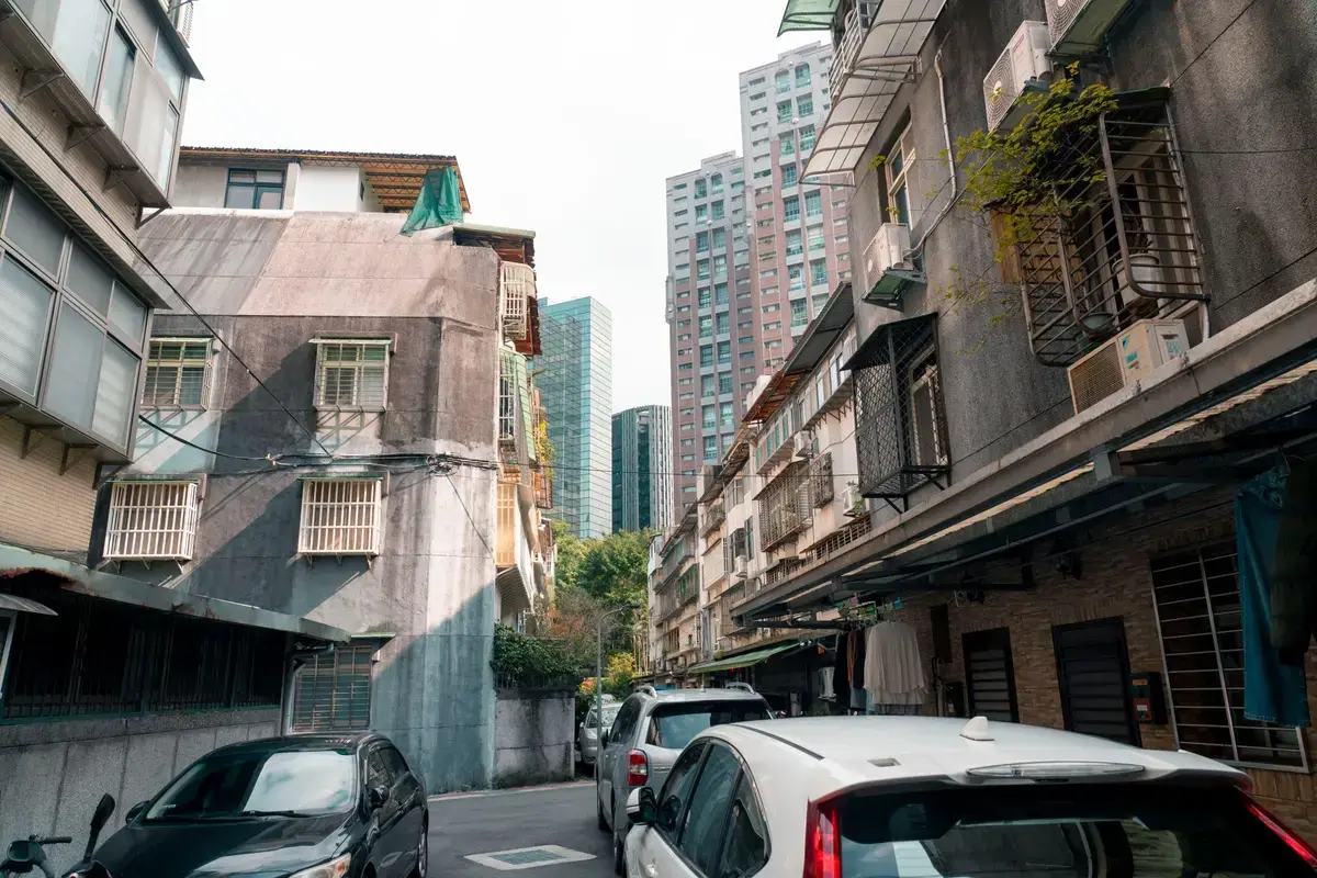 台灣街區裡的老公寓與後方住宅大樓，呈現不同屋齡住宅並存的城市景觀
