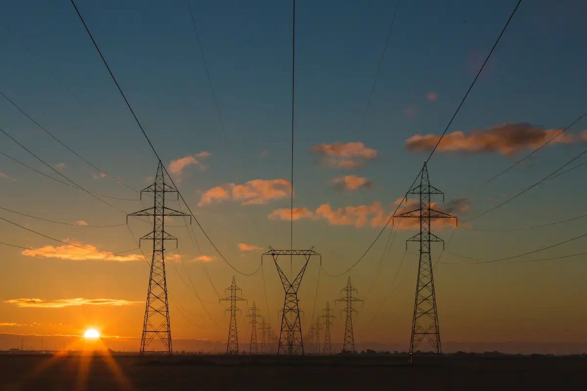 電力輸電鐵塔於夕陽下的天際線，象徵全球電力供應版圖轉變（示意圖）