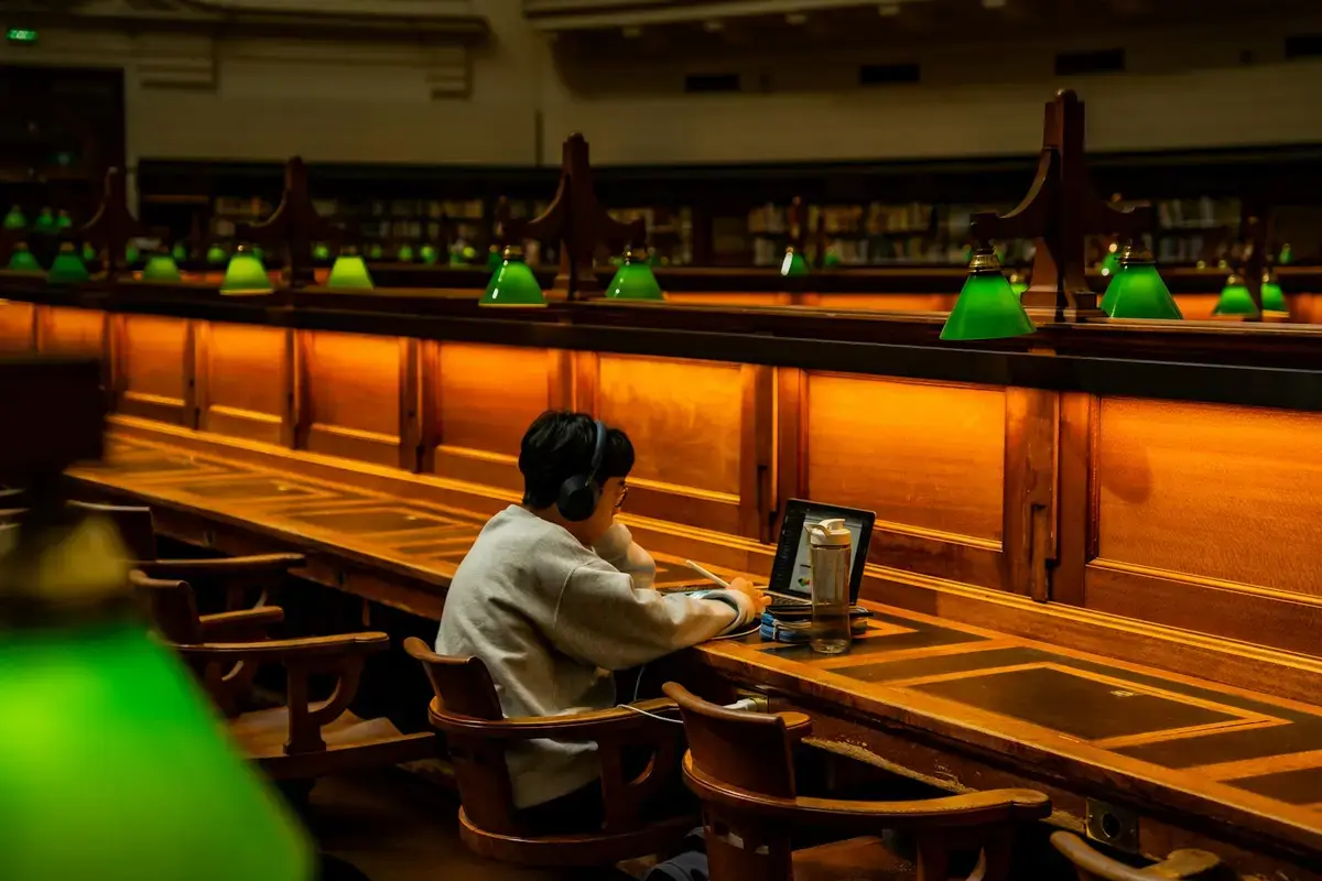大學圖書館書桌上的筆電與學生證，象徵學生方案申請前的身分查核