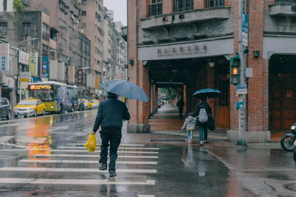 雨天台灣街頭有人撐著摺疊傘，呈現日常雨具使用場景