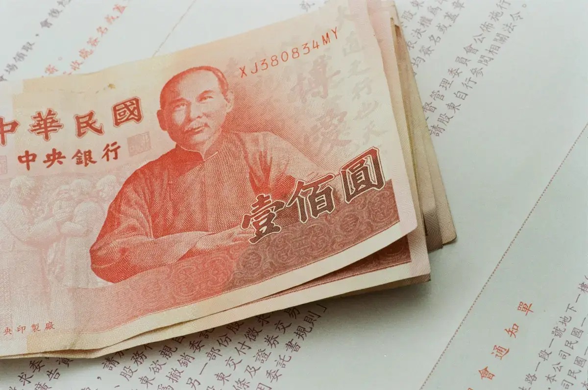 新台幣紙鈔放在中文文件上，呈現普發現金等待預算審議的情境