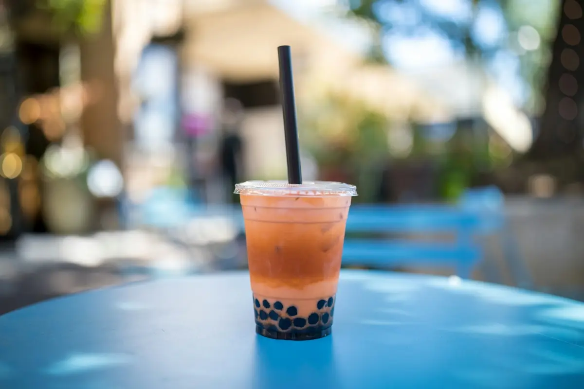 桌面上的珍珠奶茶外帶杯與黑色粗吸管（示意圖）