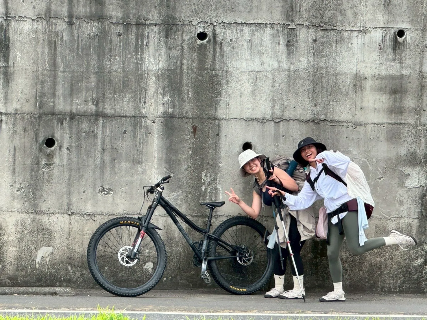 林曉彤與夥伴在街道旁停下腳步，身旁放著單車與旅程裝備
