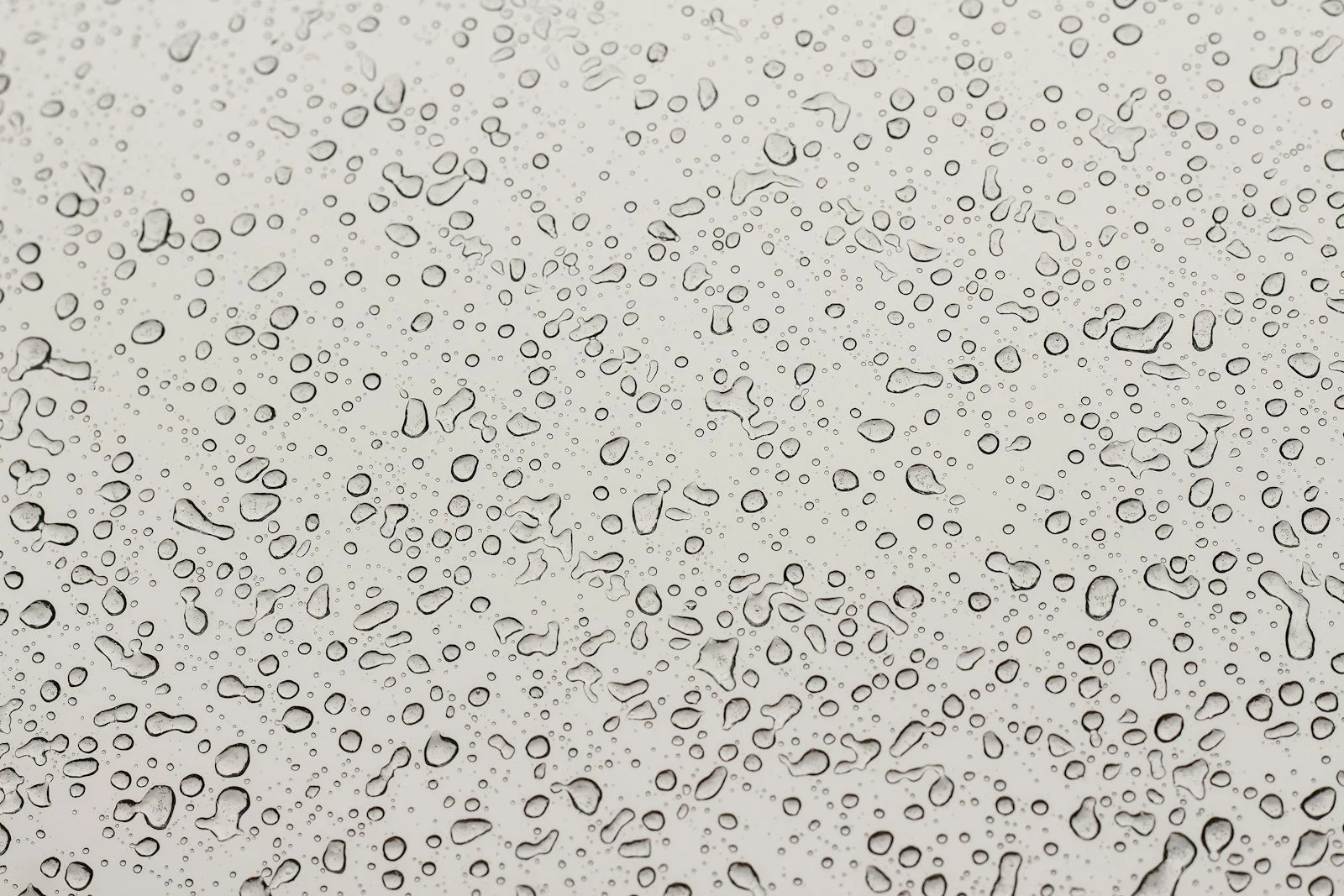 淺色表面上佈滿大小不一的水珠，光線柔和。