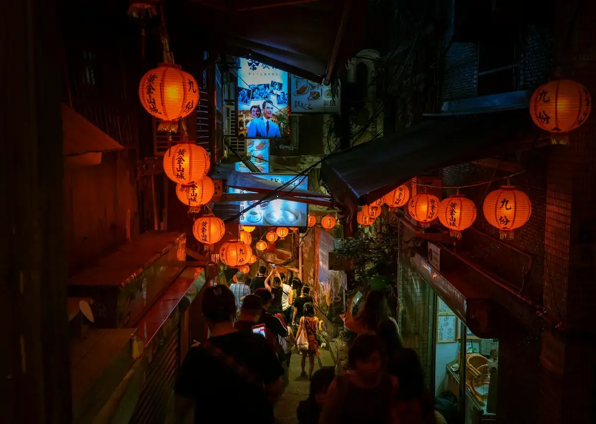 夜市街道上方懸掛彩色燈籠，呈現台灣地方夜市的夜間景象（示意圖）