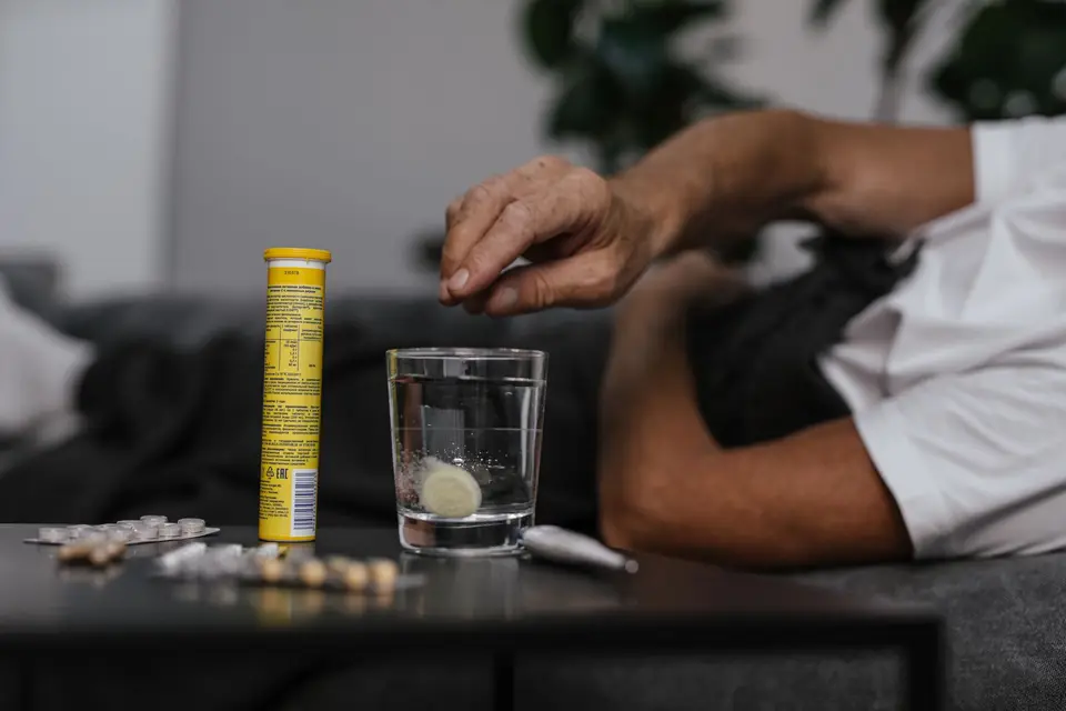 一位長者在家中準備服藥,旁邊放著水杯