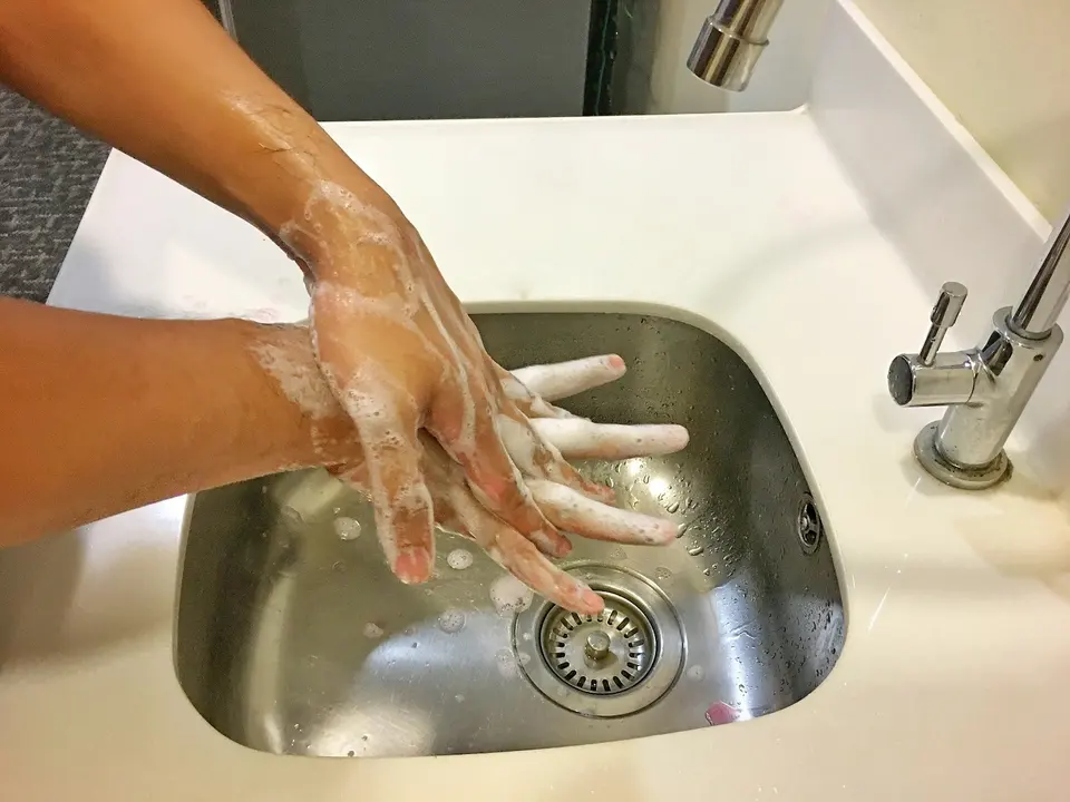 雙手在水槽用肥皂仔細搓洗,旁邊有水龍頭