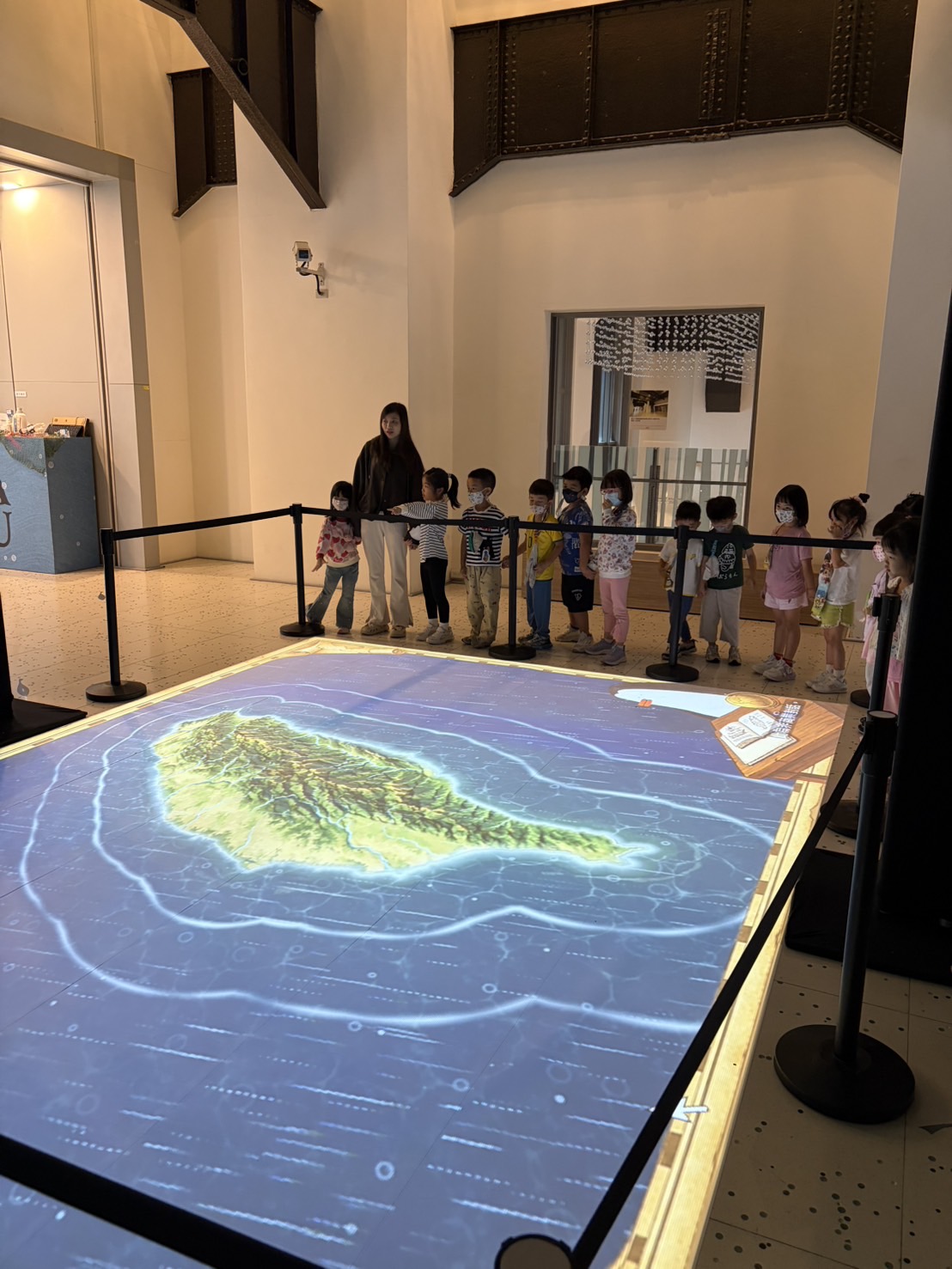 兒童站在臺灣形狀的地面投影前,觀看海洋互動展演