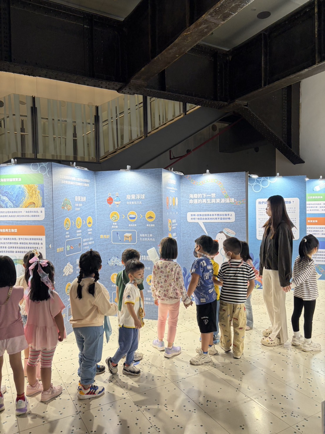 親子觀眾在海洋廢棄物展板前閱讀海洋循環與回收資訊