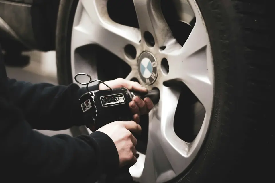 維修人員使用工具檢查汽車輪圈與輪胎