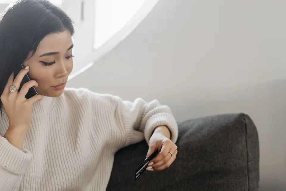 民眾拿著信用卡在電話中聯絡銀行客服