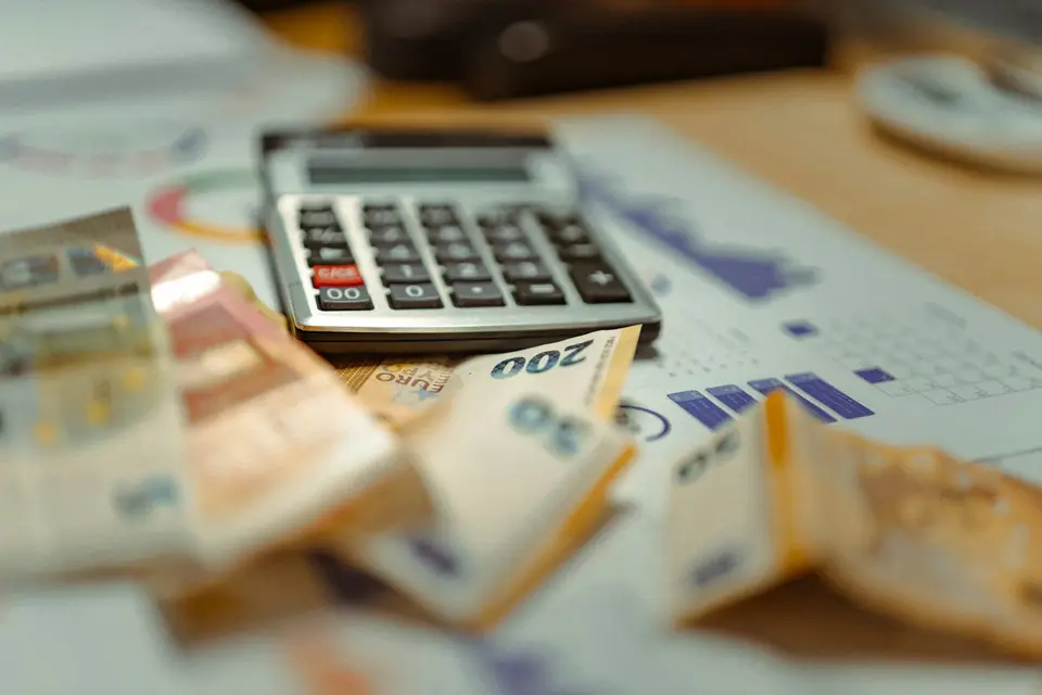 把股息分成支出、稅費預留與再投資,現金流才有明確用途(示意圖) 計算機、歐元鈔票與財務圖表呈現現金流分配的情境