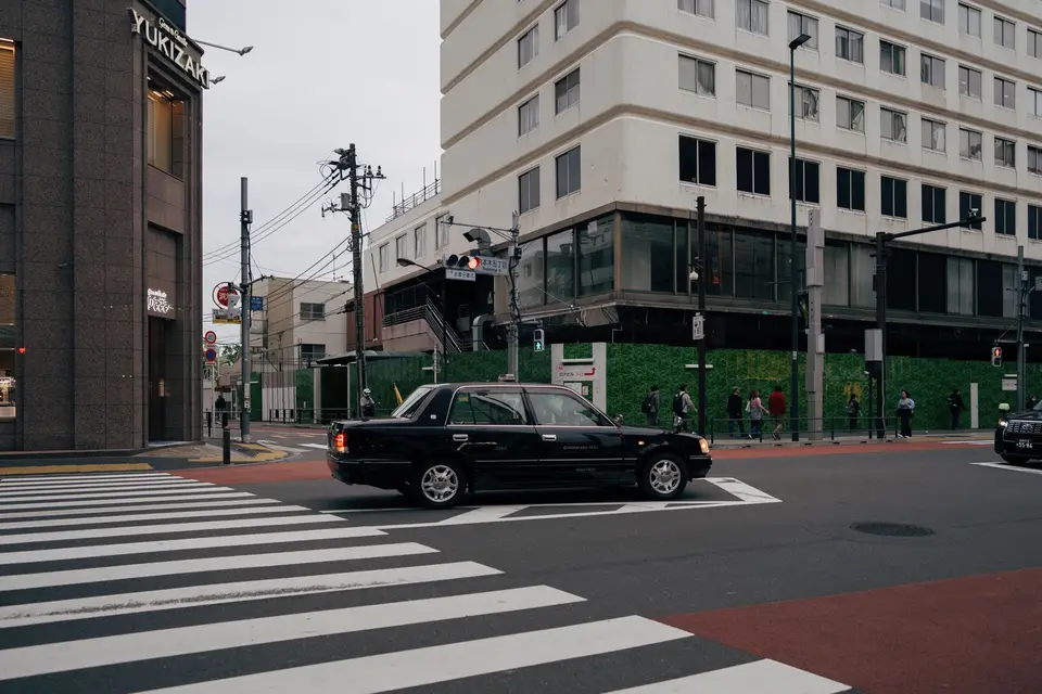 汽車穿越市區斑馬線，行人在路旁等候