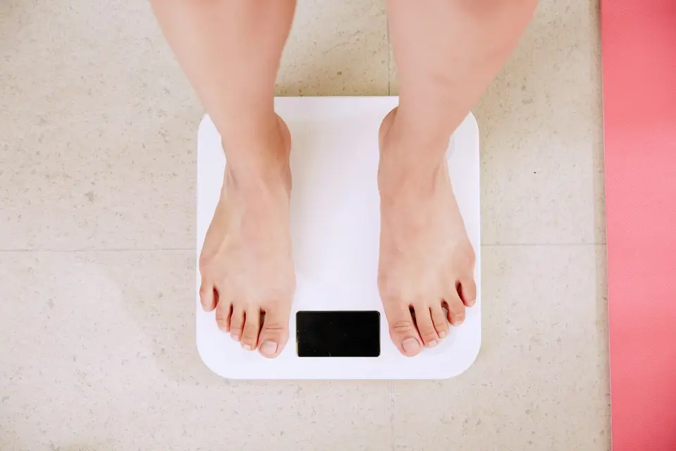 用每週體重趨勢校準赤字幅度,避免只看單日數字(示意圖) 浴室體重計旁放著月曆與健康餐計畫,呈現以每週體重趨勢校準溫和熱量赤字