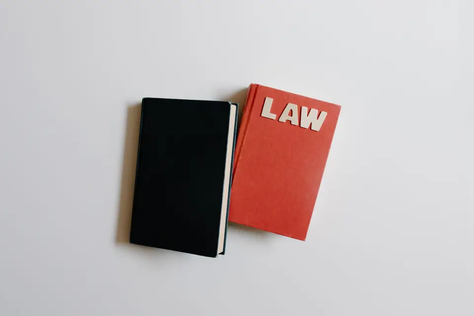 法律書籍、眼鏡與筆記放在桌上,呈現閱讀法律扶助服務說明的情境