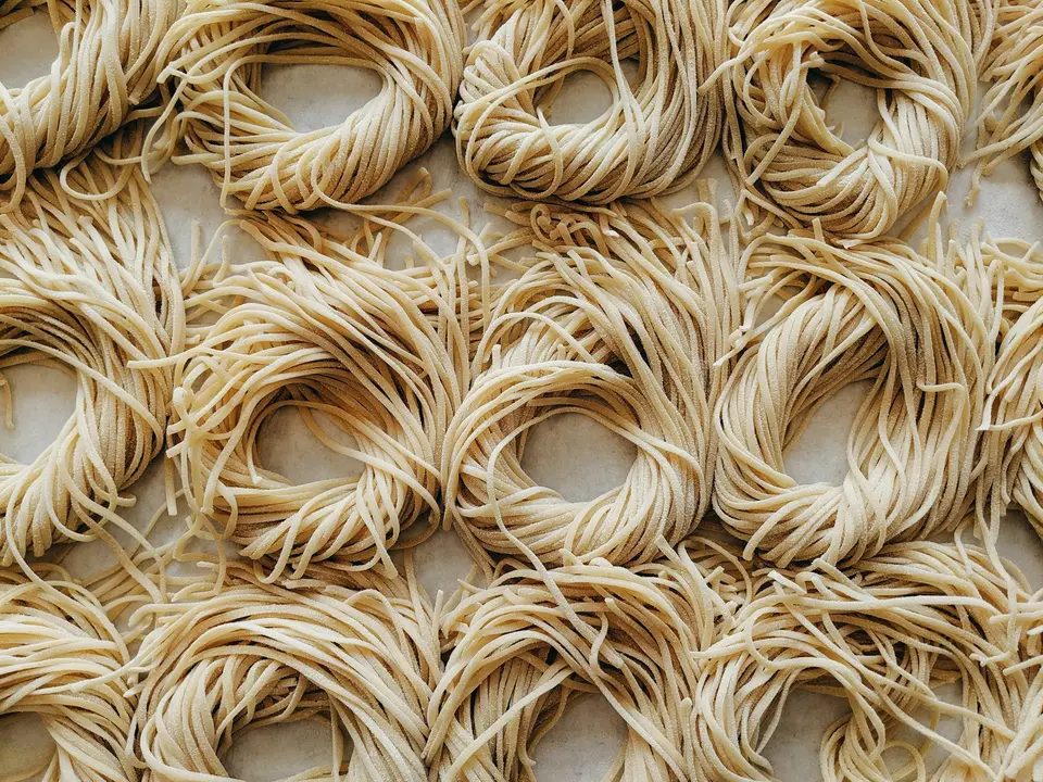 食品製程中以熱水與網籃處理麵條的近距離畫面,呈現麵體加熱與復水概念(示意圖)