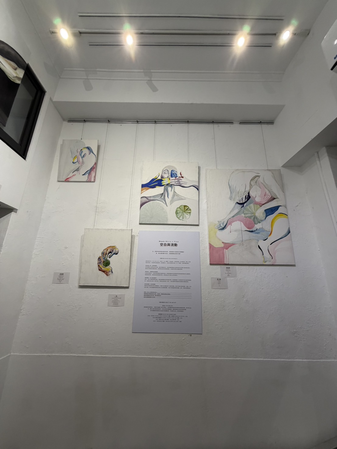 《空白與流動》展場牆面陳列多幅畫作,中央展示展覽文字。