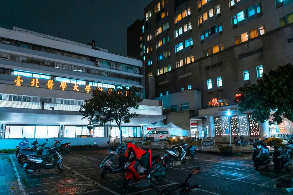 台灣醫療院所急診入口的明亮夜間場景，呈現肝指數異常合併症狀時的就醫動線，沒有可辨識人物