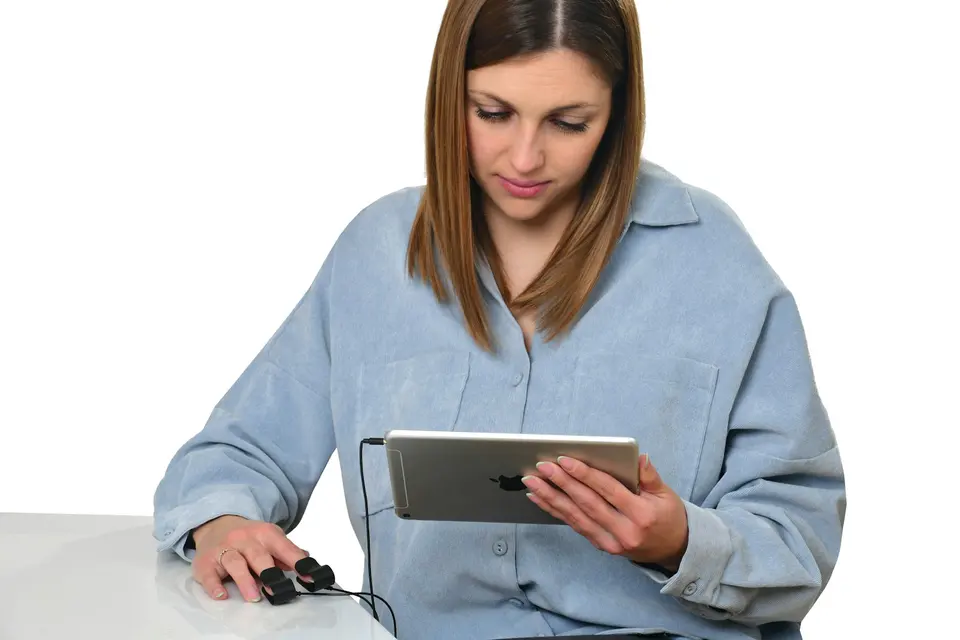 年輕女性坐在白色背景前,手指夾著血氧感測器,手持 iPad 查看健康數據