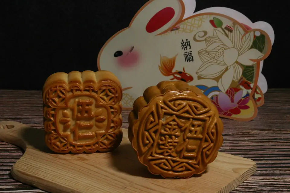 月餅與兔形節慶裝飾放在木桌上，呈現中秋應景食物。