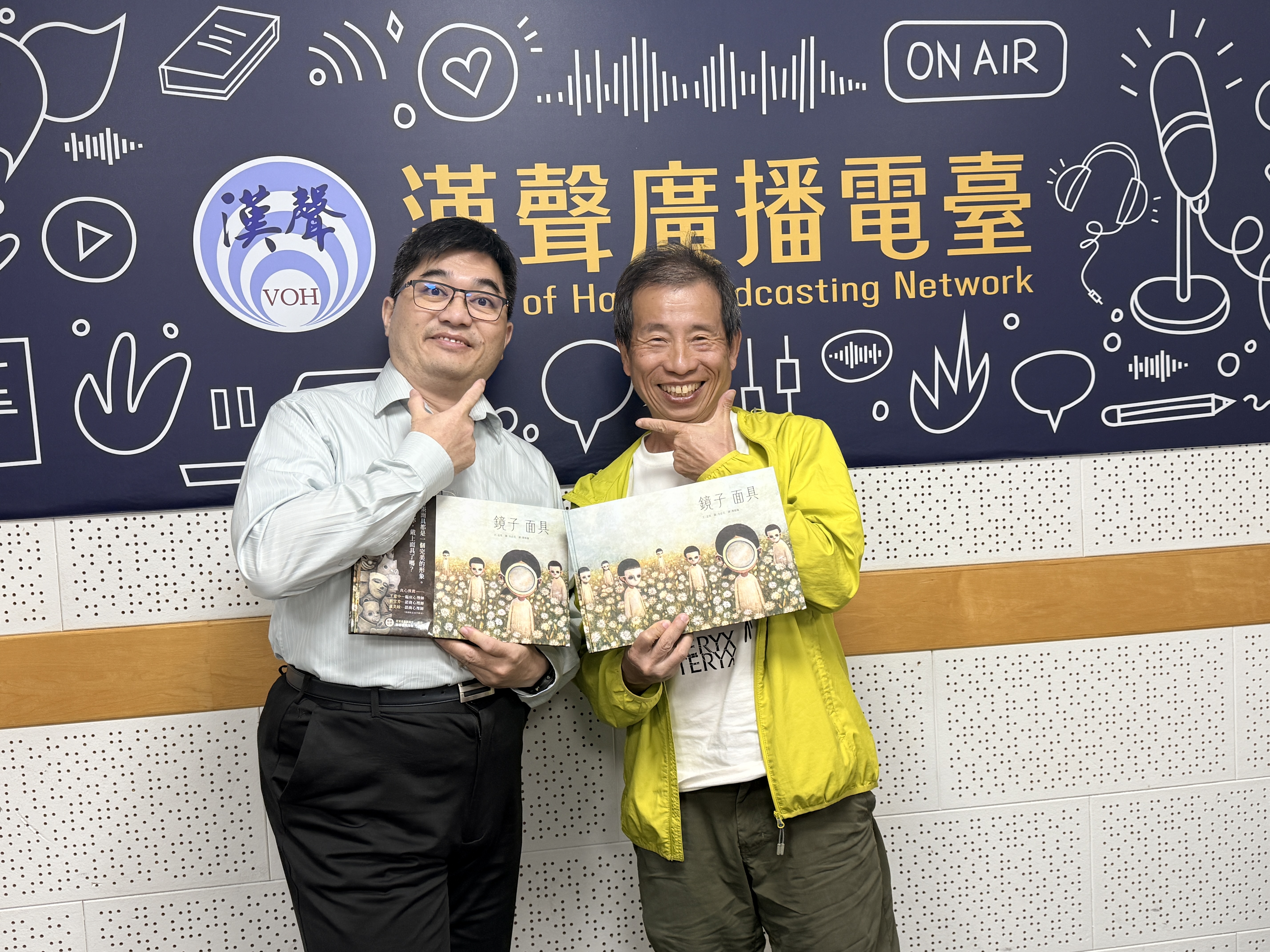 錄音室中，林以正老師及Simon展示《鏡子面具》繪本