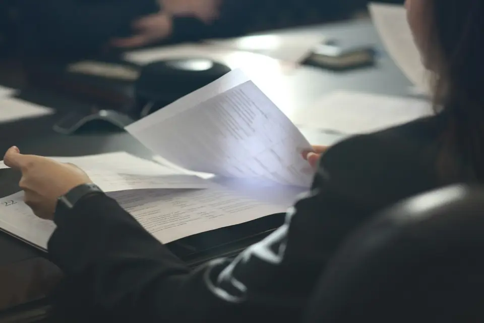 桌前有人檢視文件與筆記型電腦，呈現查閱帳戶設定資料的情境