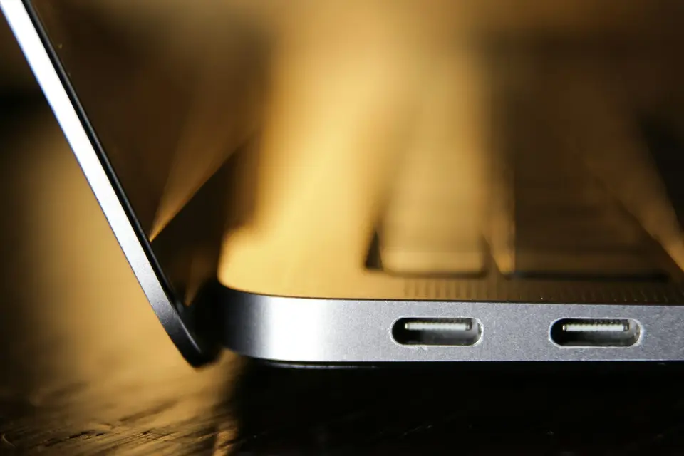 USB-C 充電器插在筆電側邊的畫面，呈現充電器進入日常生活的情境（Photo by dlxmedia.hu on Unsplash，示意圖）