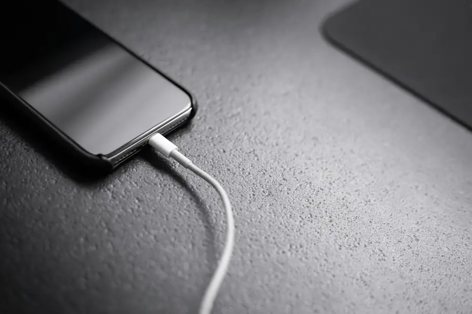 小型 USB PD 充電器、手機與筆電放在桌面，呈現現代充電器的產品形態（Photo by Andreas Haslinger on Unsplash，示意圖）