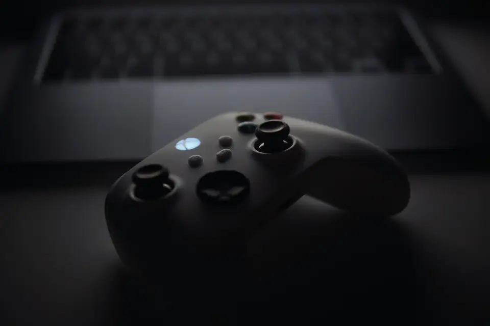 遊戲掌機與筆電放在桌面上，呈現遊戲庫與家庭共享的數位遊戲情境