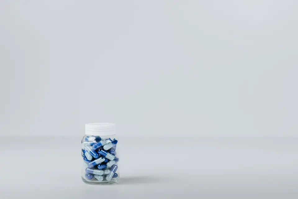 保健食品膠囊與瓶罐放在桌面上，呈現補充品配方與標示需要拆開閱讀的情境