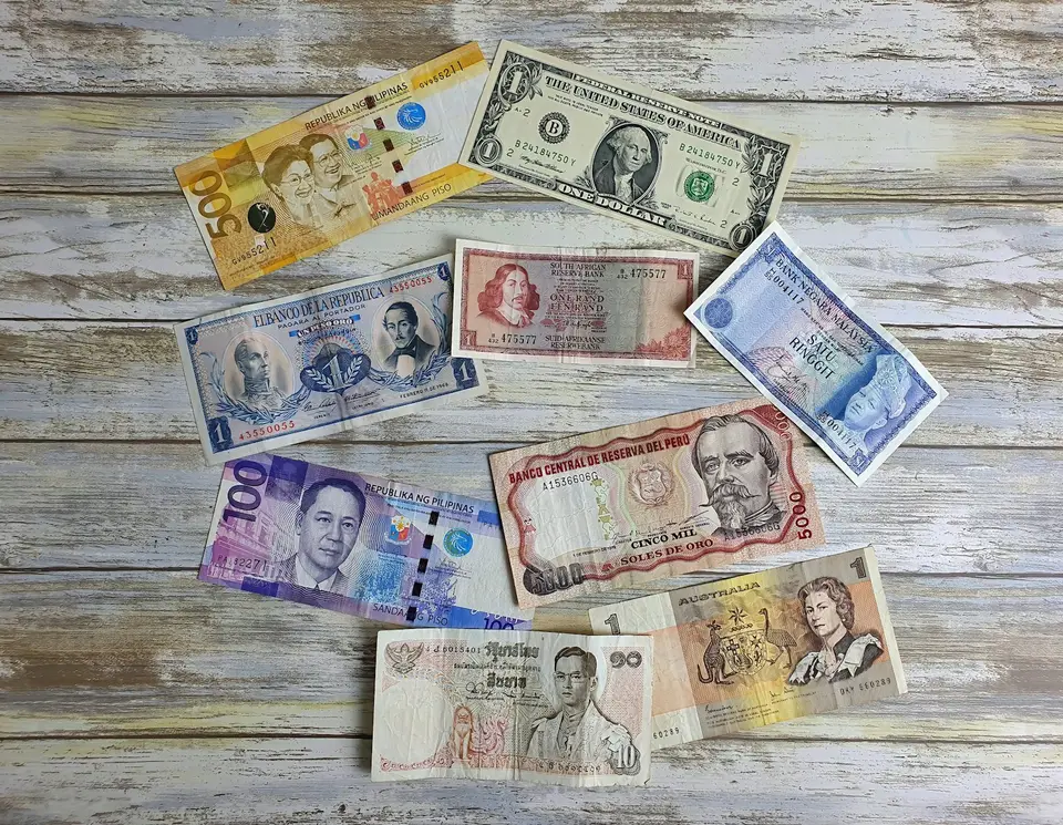 桌面上擺放多國貨幣紙鈔與計算資料