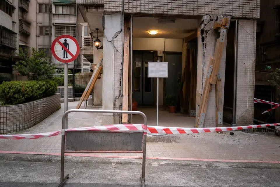 震後建物外圍以警示帶隔開，入口旁有禁止進入標示，呈現受損建築的安全距離。