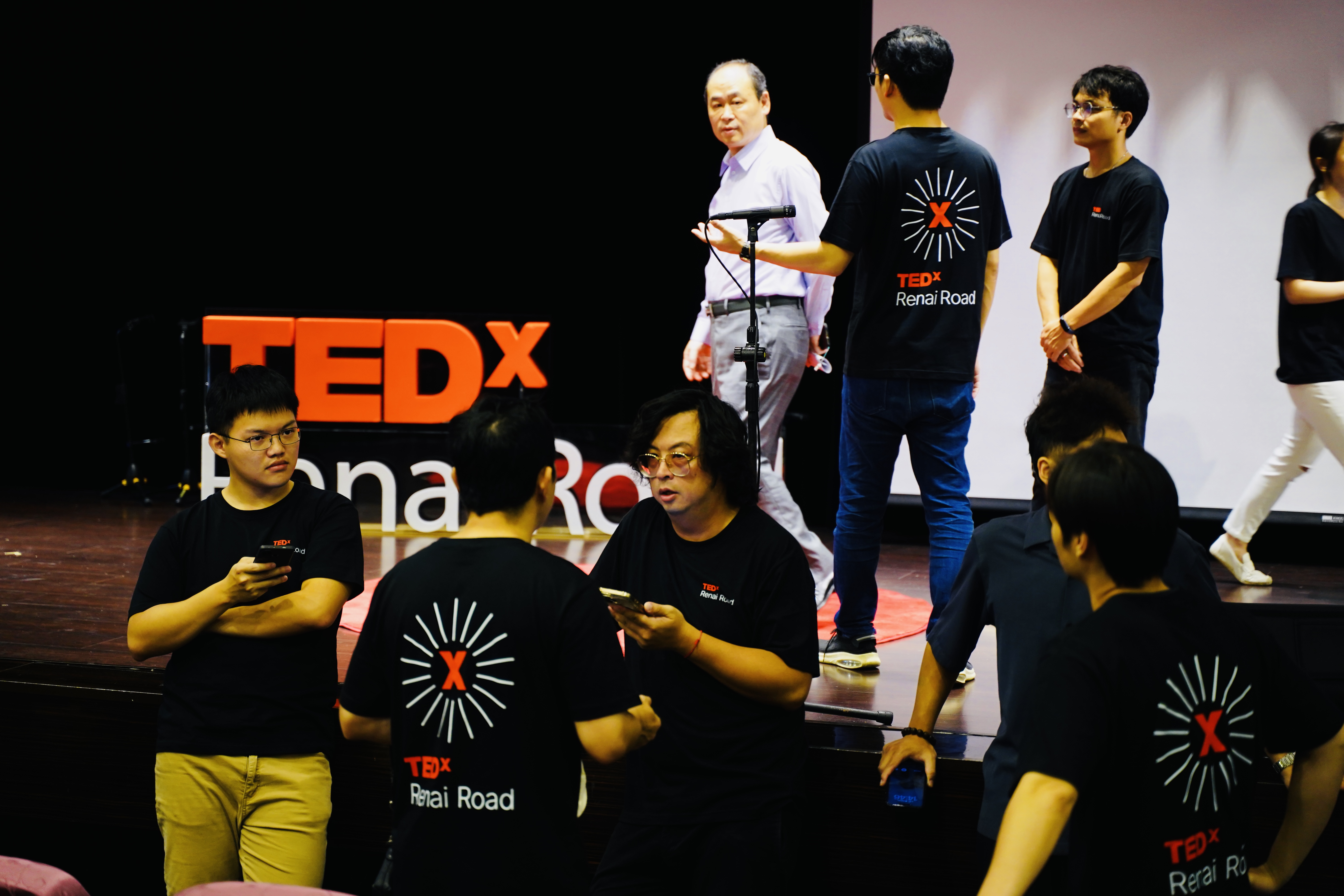 TEDxRenaiRoad舞台上的工作人員與志工正在執行現場流程,呈現舞台管理與幕後協作