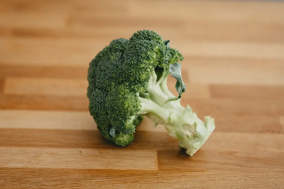 一顆新鮮綠花椰菜放在木製砧板上