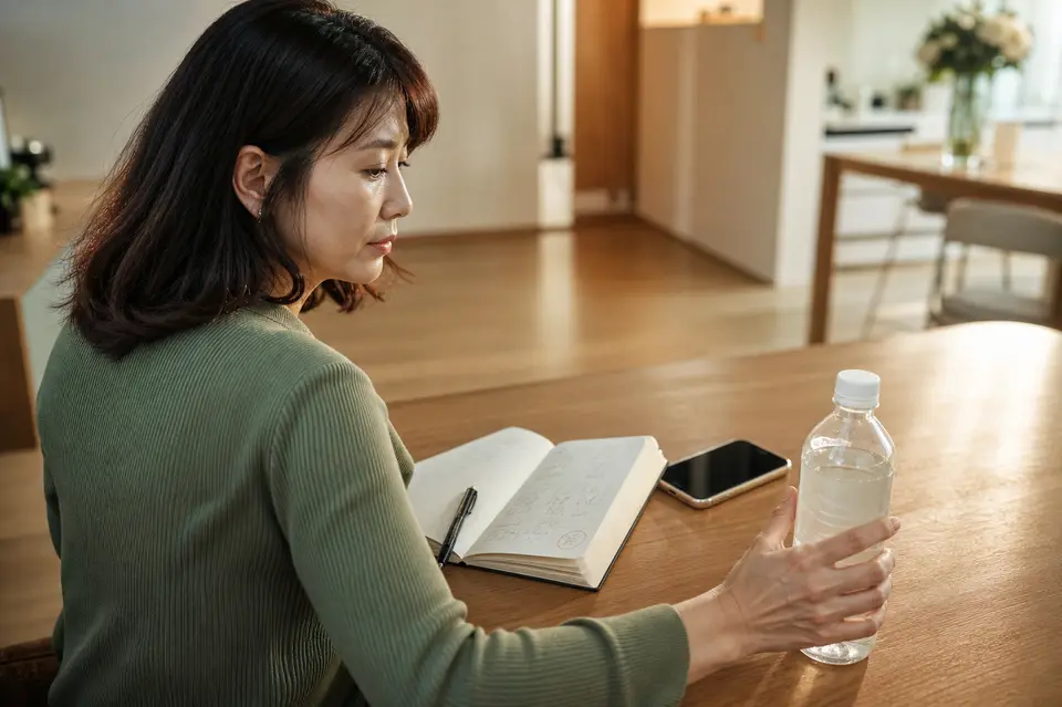 透明口服電解質液、手機與記錄症狀的筆記本放在桌上,提醒讀者辨認水瀉就醫警訊(示意圖)